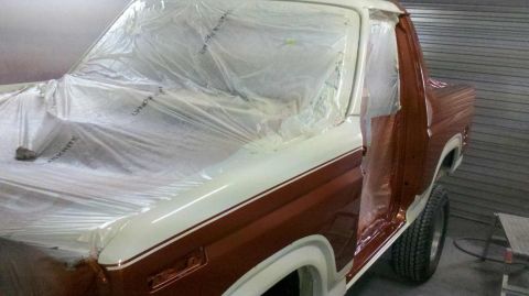 1982 Ford Bronco - This 1982 Ford Bronco is undergoing preparation for a new paint job, with its doors open and body covered in protective plastic.