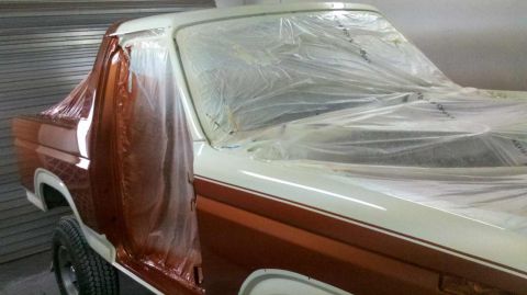 1982 Ford Bronco - A vehicle is being prepped for painting, with plastic sheeting covering most of its body.