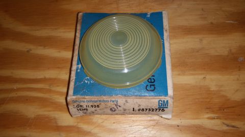 2015 Chevrolet new - A General Motors lens is shown in its original packaging on a wooden table.