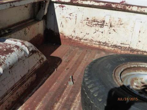 1970 Ford F-250 - The worn and weathered interior of a truck bed shows signs of rust and use, with a spare tire in the corner.