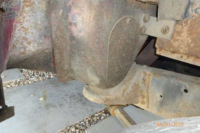close-up of rusty vehicle frame and suspension parts, showing a large metal component and a leaf spring