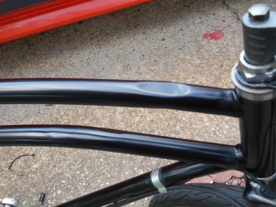 Close-up of a bicycle frame with a dented top tube and front fork.