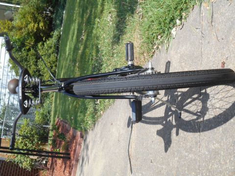 Black bicycle with sprung saddle and chain drive on concrete path.