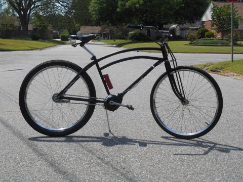 Black cruiser bicycle with a red water bottle and vintage headlight.