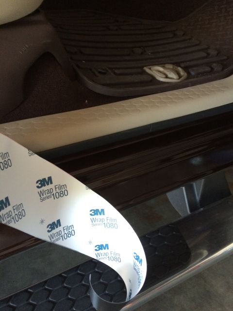 2015 Dodge 1500 - A roll of 3M Wrap Film Series 1080 is being unrolled over the interior door sill of a vehicle. The film has the 3M logo and text printed on…