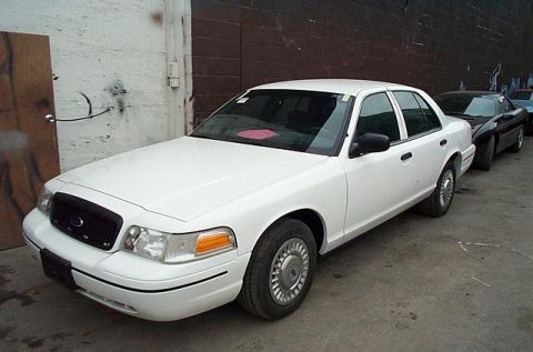 2001 Ford Crown Victoria - White 2001 Ford Crown Victoria sedan parked in a lot with other vehicles.