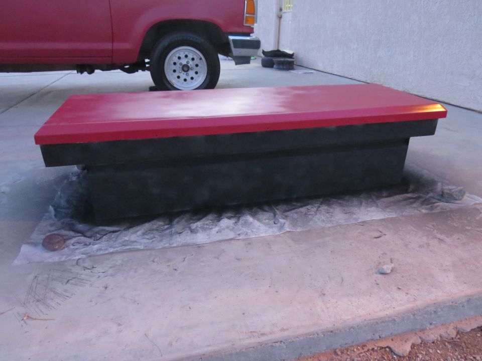 Red and black storage box next to a red Ford Ranger pickup truck.
