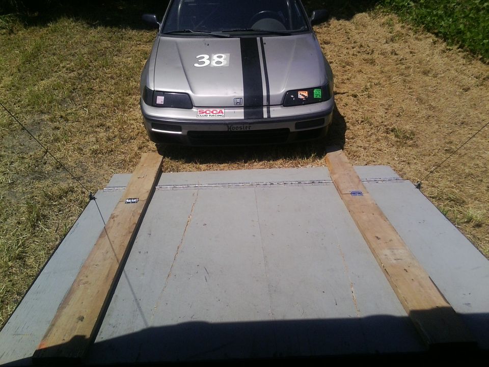 Silver and black race car with number 38 on hood, on a ramp.
