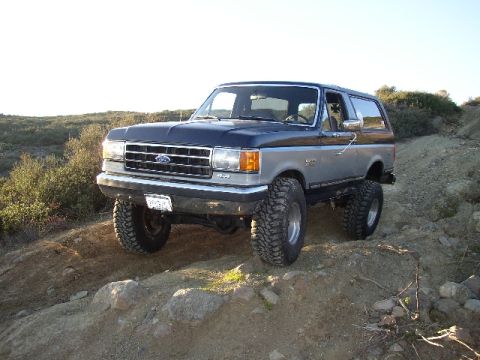 1989 Ford Bronco - This lifted 1989 Ford Bronco navigates a rocky, off-road trail under a clear sky.