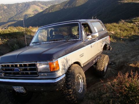 1989 Ford Bronco - Ford Bronco navigating a dirt trail in a hilly, natural landscape.