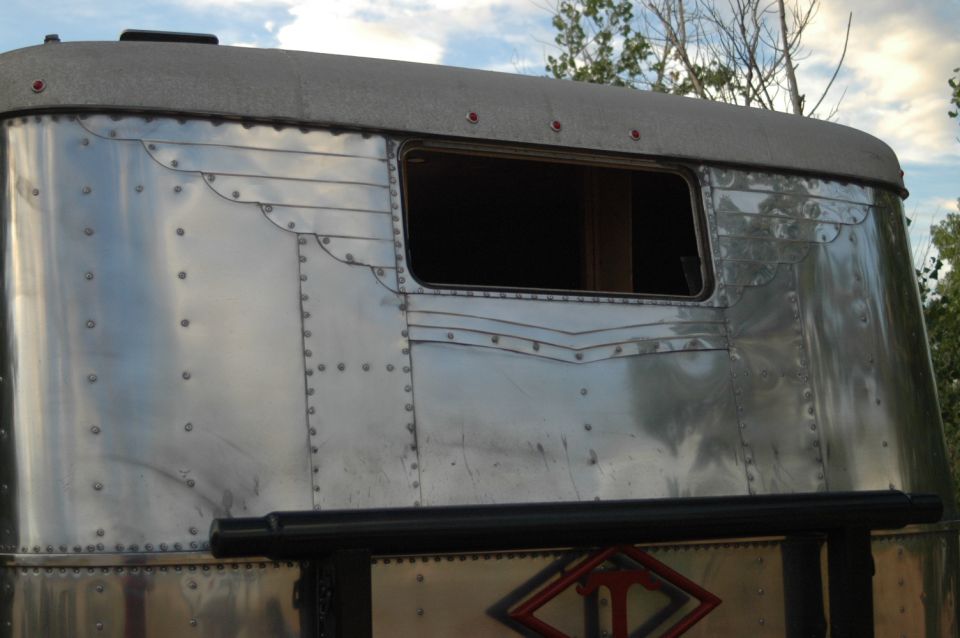 Polished aluminum trailer rear with a grey roof and a dark window.