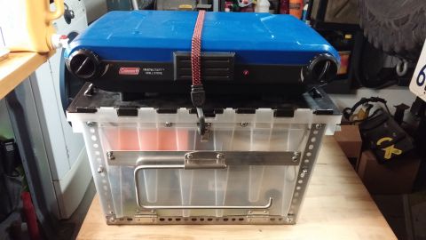 1985 Toyota 4Runner - A Coleman InstaStart Grill Stove is secured atop a clear storage bin with metal accents and handles.