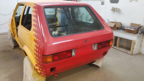 1983 Volkswagen Rabbit - Rear view of a red Volkswagen Golf Mk1 with yellow primer on the body, showing a roll cage and undergoing repairs.