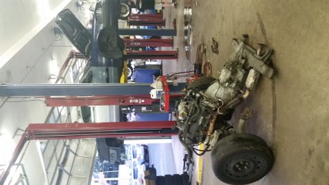 2001 Ford Crown Victoria - Engine and front subframe assembly removed from a vehicle, resting on a garage floor.