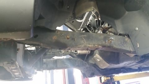 2001 Ford Crown Victoria - The undercarriage of a vehicle is shown, with visible rust on the frame and suspension parts.