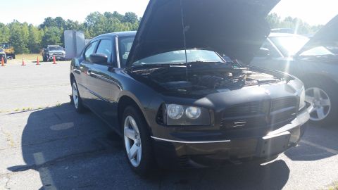 2001 Ford Crown Victoria - A black Dodge Charger is parked with its hood up, revealing the engine compartment. Another vehicle is visible to the right.