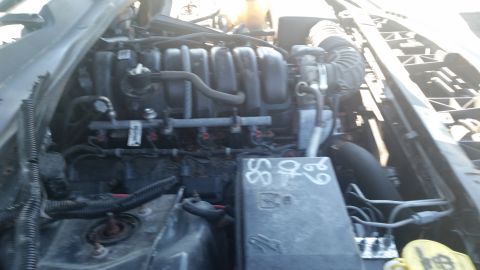 2001 Ford Crown Victoria - Close-up view of a vehicle's engine bay, showing various components and handwritten markings on a fuse box.