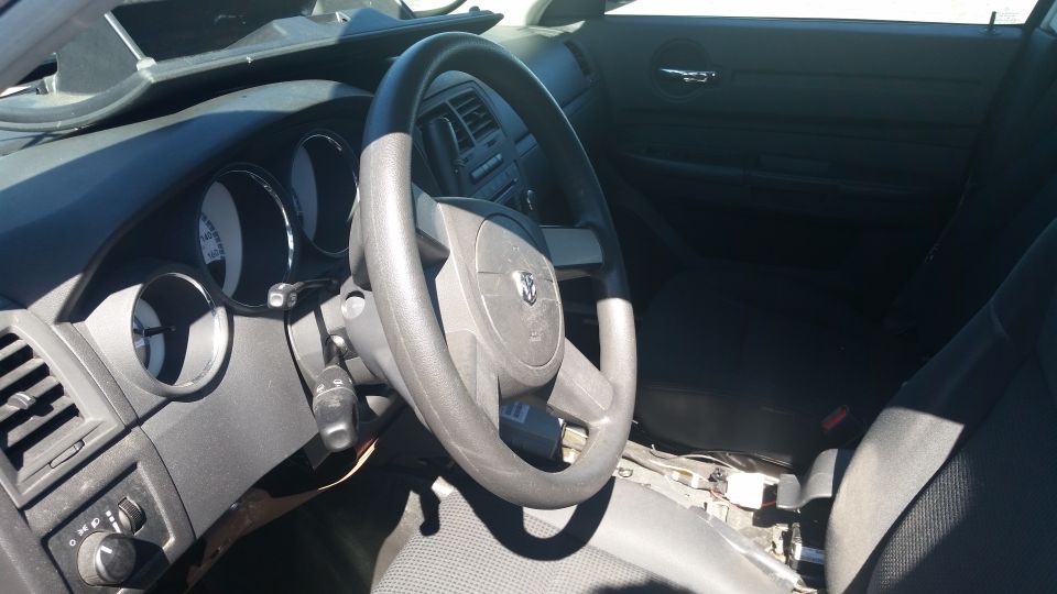 Car interior showing dashboard, steering wheel with Dodge logo, and seats. Some interior components are disassembled