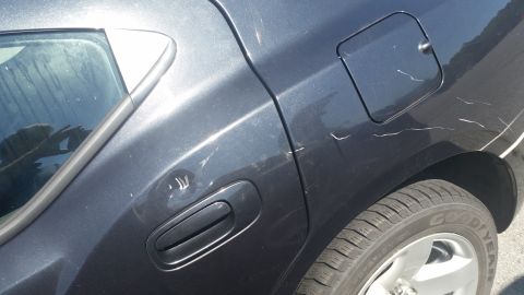 2001 Ford Crown Victoria - Scratches and a dent are visible on the rear quarter panel of a dark gray car.