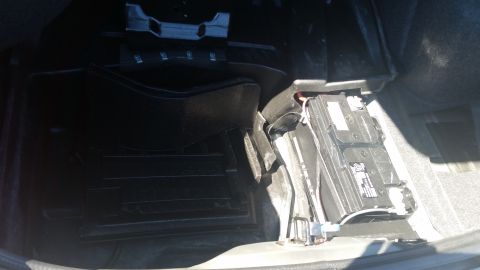 2001 Ford Crown Victoria - The trunk of a car with the battery compartment exposed, revealing wiring and the battery housing.