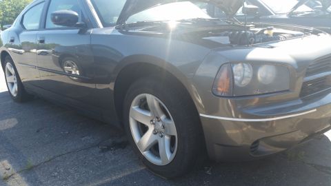 2001 Ford Crown Victoria - A gray Dodge Charger sits with its hood open, revealing the engine compartment.