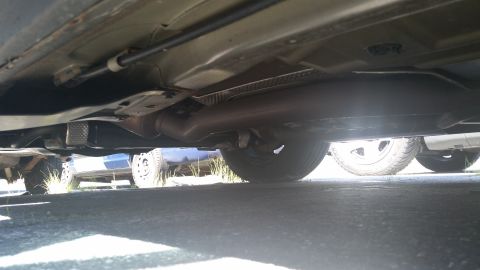 2001 Ford Crown Victoria - Undercarriage view showing the exhaust system and frame of a vehicle parked outdoors.