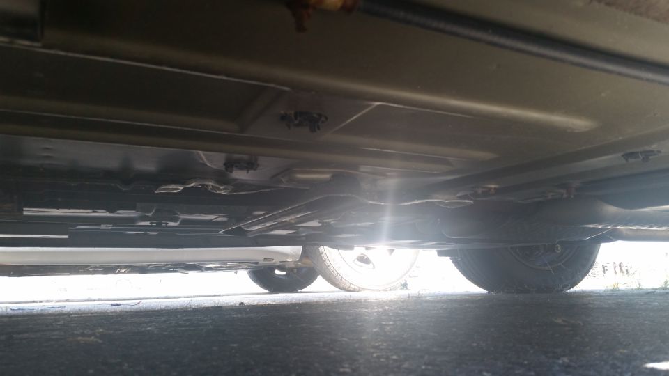 Underside view of a car, showing the frame, exhaust, and tires