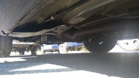 2001 Ford Crown Victoria - A low-angle view of the undercarriage of a vehicle, with another car partially visible behind it.