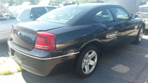 2001 Ford Crown Victoria - A dark-colored Dodge Charger sits in a salvage yard, its rear quarter panel and taillight clearly visible.