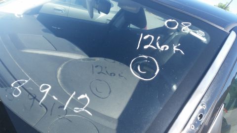 2001 Ford Crown Victoria - White chalk markings on a car's windshield indicate mileage and dates.