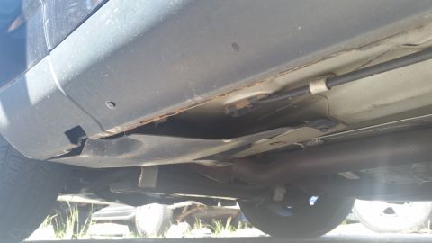 2001 Ford Crown Victoria - The underside of a vehicle shows some rust on the rocker panel and exhaust components.