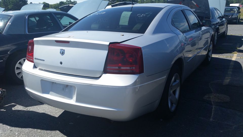 Silver Dodge Charger rear view, dent on trunk lid, visible "Charger" text