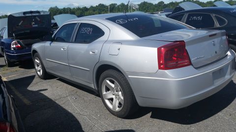 2001 Ford Crown Victoria - Silver Dodge Charger in a junkyard with other cars, some with hoods open.