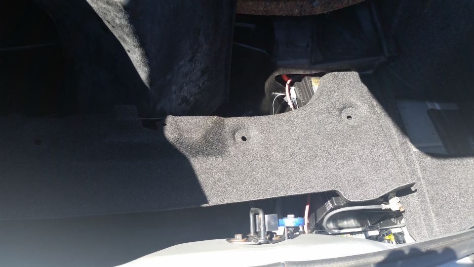 Car trunk interior with carpeted panels and some wiring visible