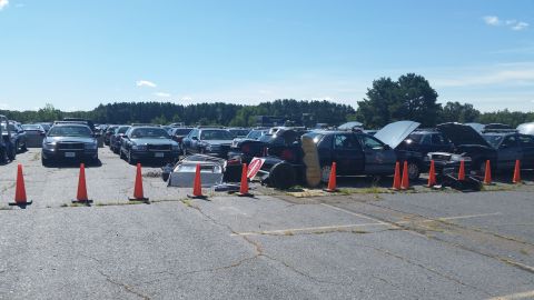 2001 Ford Crown Victoria - Multiple police vehicles are parked in a lot under a clear blue sky.
