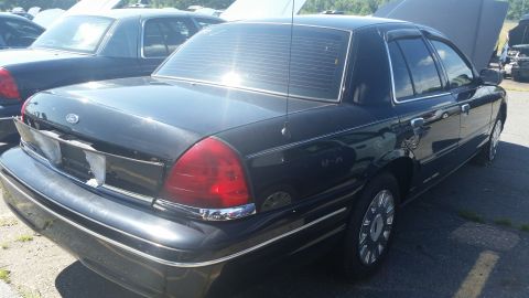 2001 Ford Crown Victoria - A black 2001 Ford Crown Victoria is parked in a lot with other vehicles, hoods up on some.