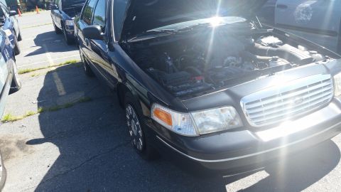 2001 Ford Crown Victoria - A black Ford Crown Victoria is parked outside with its hood open, revealing the engine compartment.