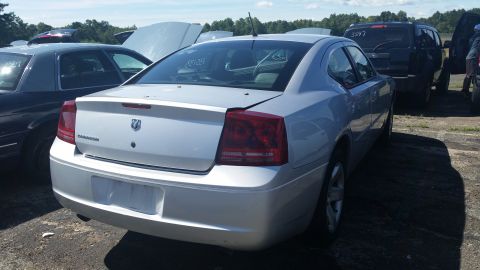 2001 Ford Crown Victoria - A silver Dodge Charger is seen from the rear in a junkyard setting.