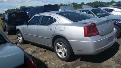 2001 Ford Crown Victoria - A silver Dodge Charger is parked in a lot with other vehicles, including a police car.