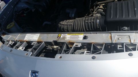2001 Ford Crown Victoria - Photograph of an engine bay radiator support with small underhood warning labels, not a classifiable document.