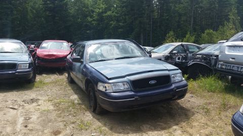 2001 Ford Crown Victoria - Photograph of a blue Ford Crown Victoria among other cars at a salvage yard, not a technical document.