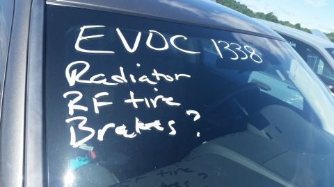 2001 Ford Crown Victoria - Photograph of a windshield with grease-pencil notes listing radiator, RF tire, and brakes, not a technical document.