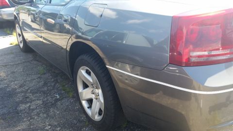 2001 Ford Crown Victoria - Photo of the rear driver-side quarter panel, wheel, and taillight of a gray Dodge Charger.