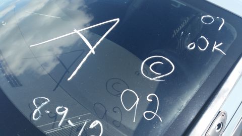 2001 Ford Crown Victoria - Photo of a vehicle window with white grease-pencil inventory markings such as A, 07, 00K, 92.