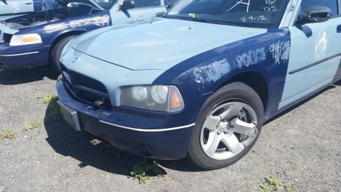 2001 Ford Crown Victoria - Photo of the front fender and headlight of a two-tone blue Dodge Charger in a salvage yard.