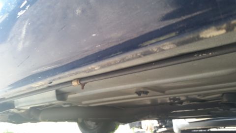 2001 Ford Crown Victoria - Photo of the underside rocker panel and brake or fuel line of a dark blue vehicle.