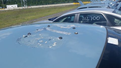 2001 Ford Crown Victoria - Photo of a car hood marked with stock number 112700, parked among other vehicles in an outdoor lot, not a document.