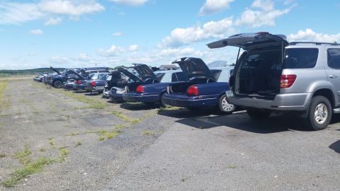 2001 Ford Crown Victoria - Photo of a line of vehicles with open trunks parked in an outdoor lot, not a document.