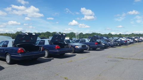 2001 Ford Crown Victoria - Photo of a row of sedans with open trunks in an outdoor lot, not a document.