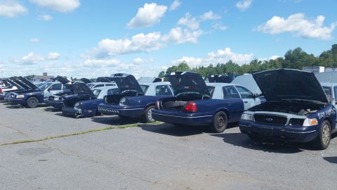 2001 Ford Crown Victoria - Photo of multiple vehicles with open hoods and trunks parked in a lot, not a document.